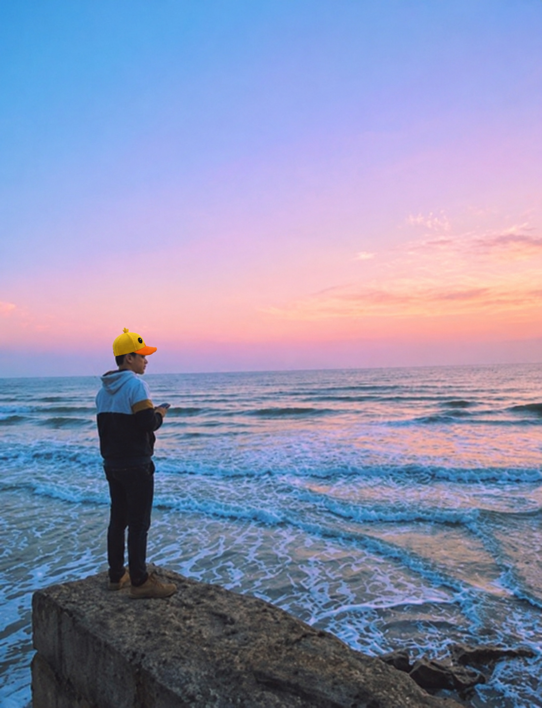 Gorra amarilla de pato frente al mar y un cielo rosado